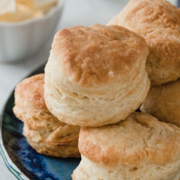 Fluffy homemade biscuits stacked up on a plate.