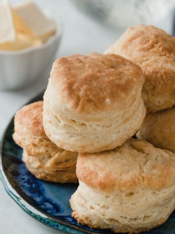Fluffy homemade biscuits stacked up on a plate.