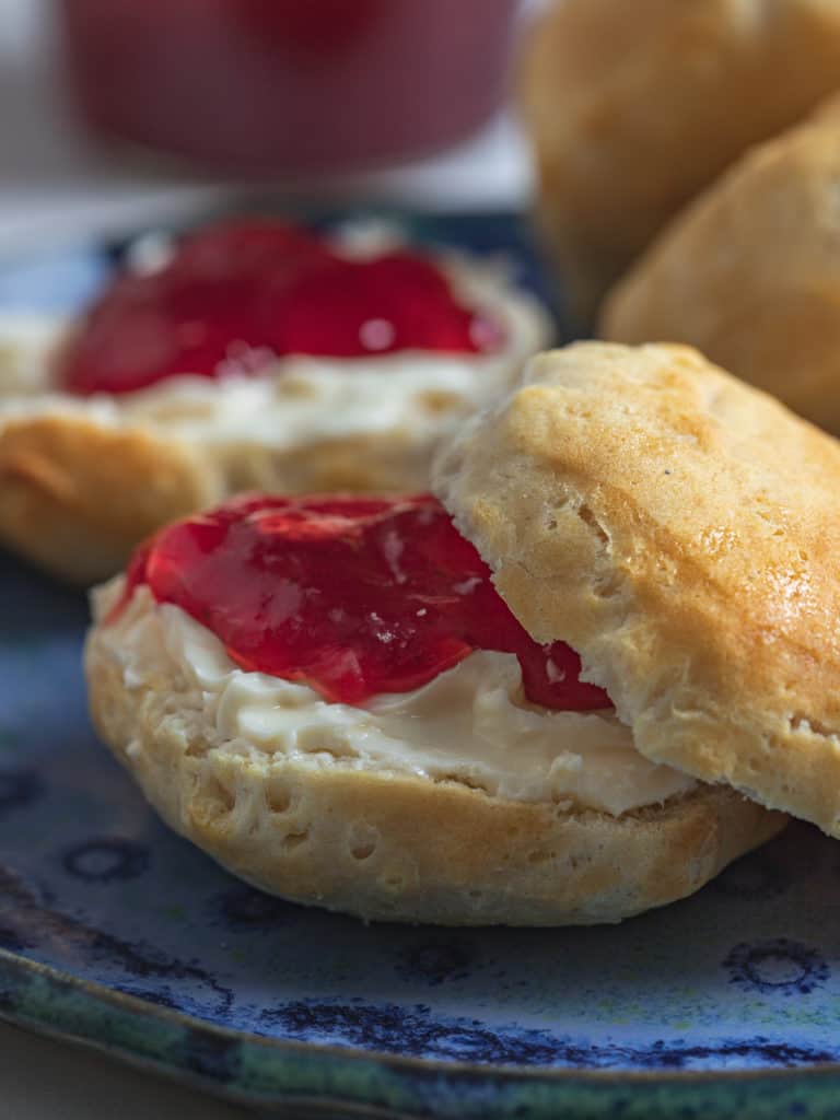 Fluffy buttermilk biscuits with butter and jam on a plate.