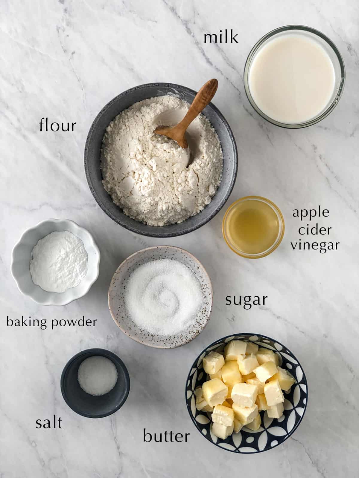 Ingredients for vegan biscuits in bowls on a work surface.