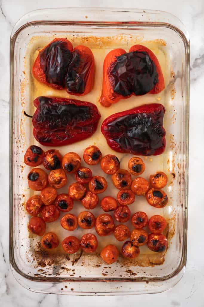 Red peppers and cherry tomatoes blackened in a lasagna pan.