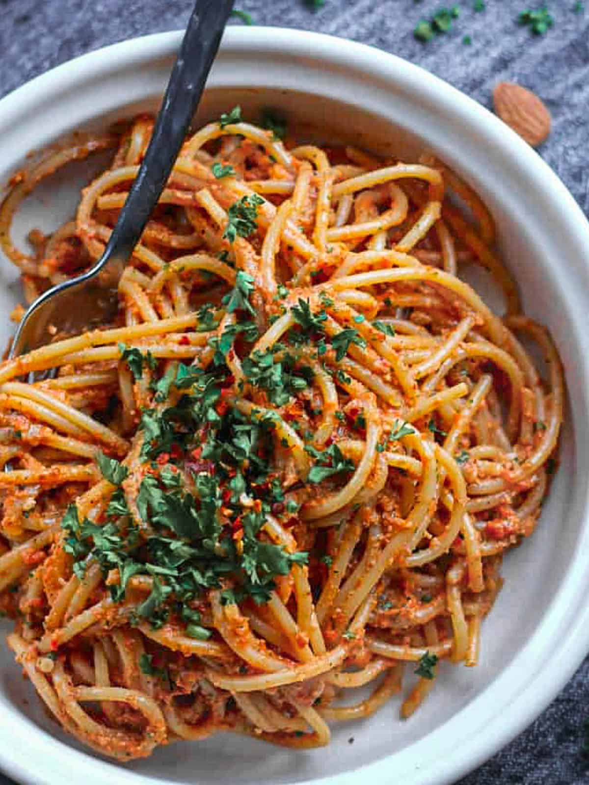 Romesco pasta in bowl topped with chopped parsley.