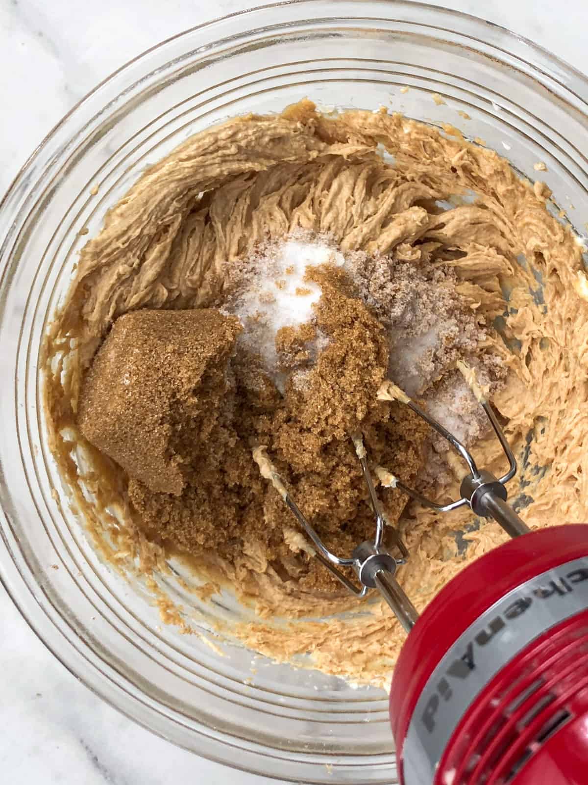 Peanut butter cookie ingredients being mixed in bowl with hand blender.