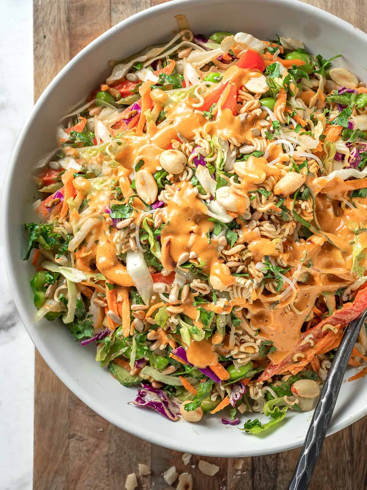 Thai shredded crunch salad in a bowl with spicy peanut sauce on top.
