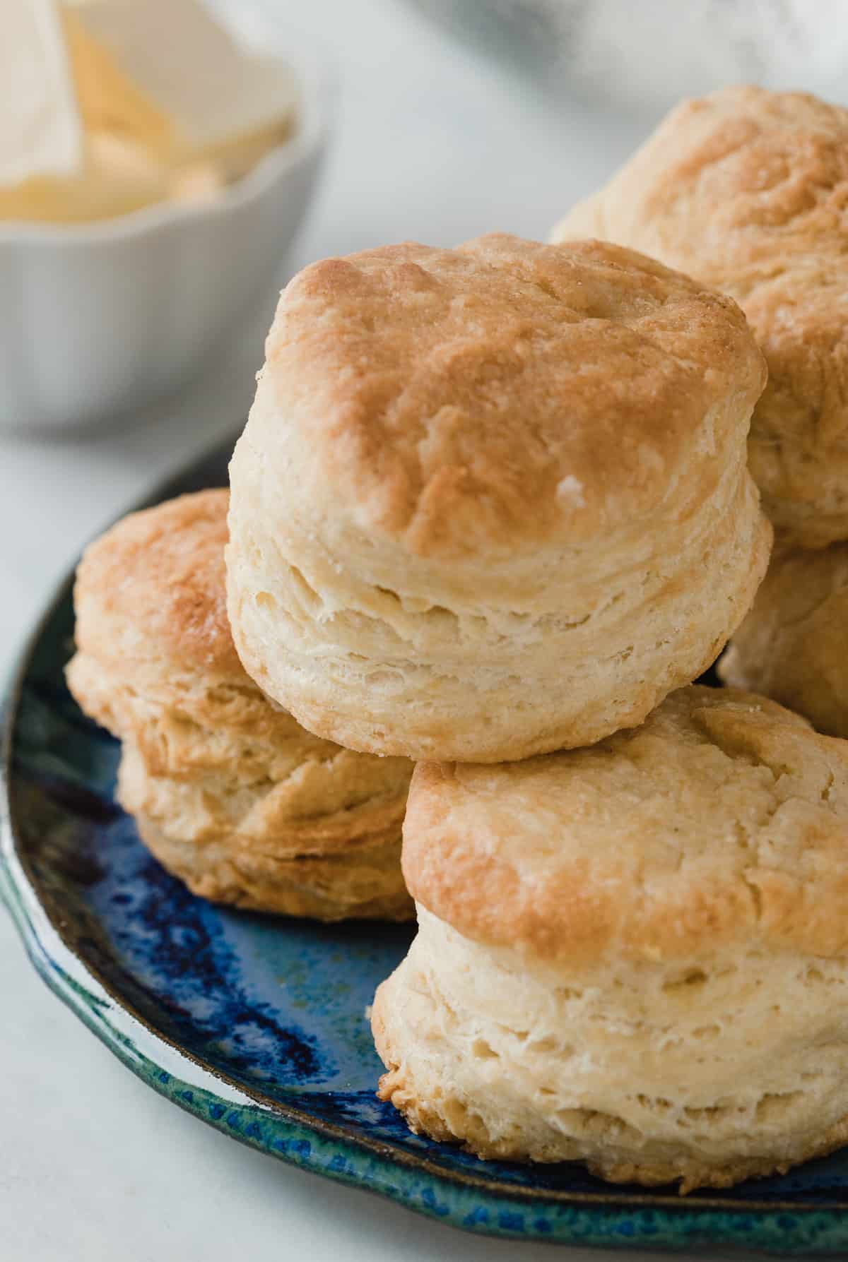 Fluffy homemade biscuits stacked up on a plate.