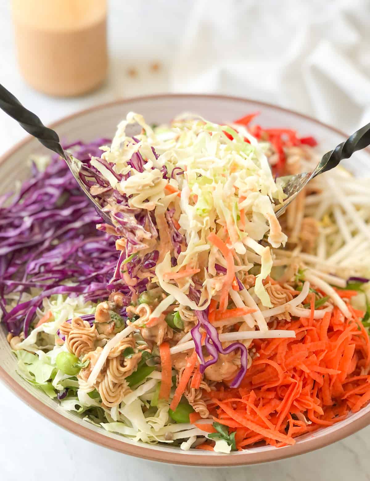 Crunch salad being tossed with peanut dressing.