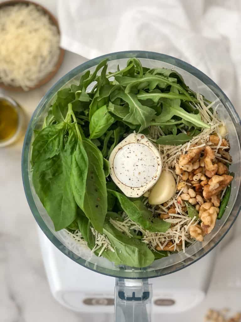 Basil, walnuts, and cheese in a food processor to make vegan pesto sauce.