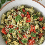Bowl of veggie pasta pesto with fresh basil leaves.