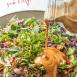 Spicy peanut sauce being poured on a bowl of Thai coleslaw. salad