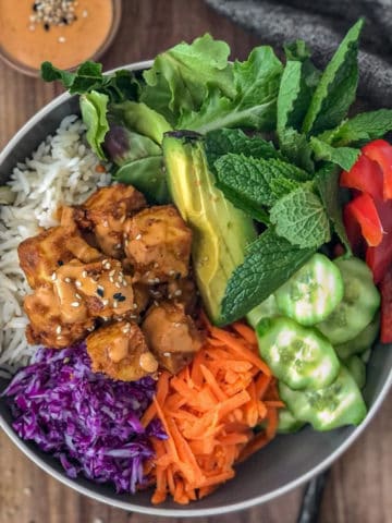 Tofu, avocado, carrot, and cucumber noodle bowl with peanut sauce.