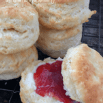 Stack of vegan biscuits with one split open slathered in butter and jam.