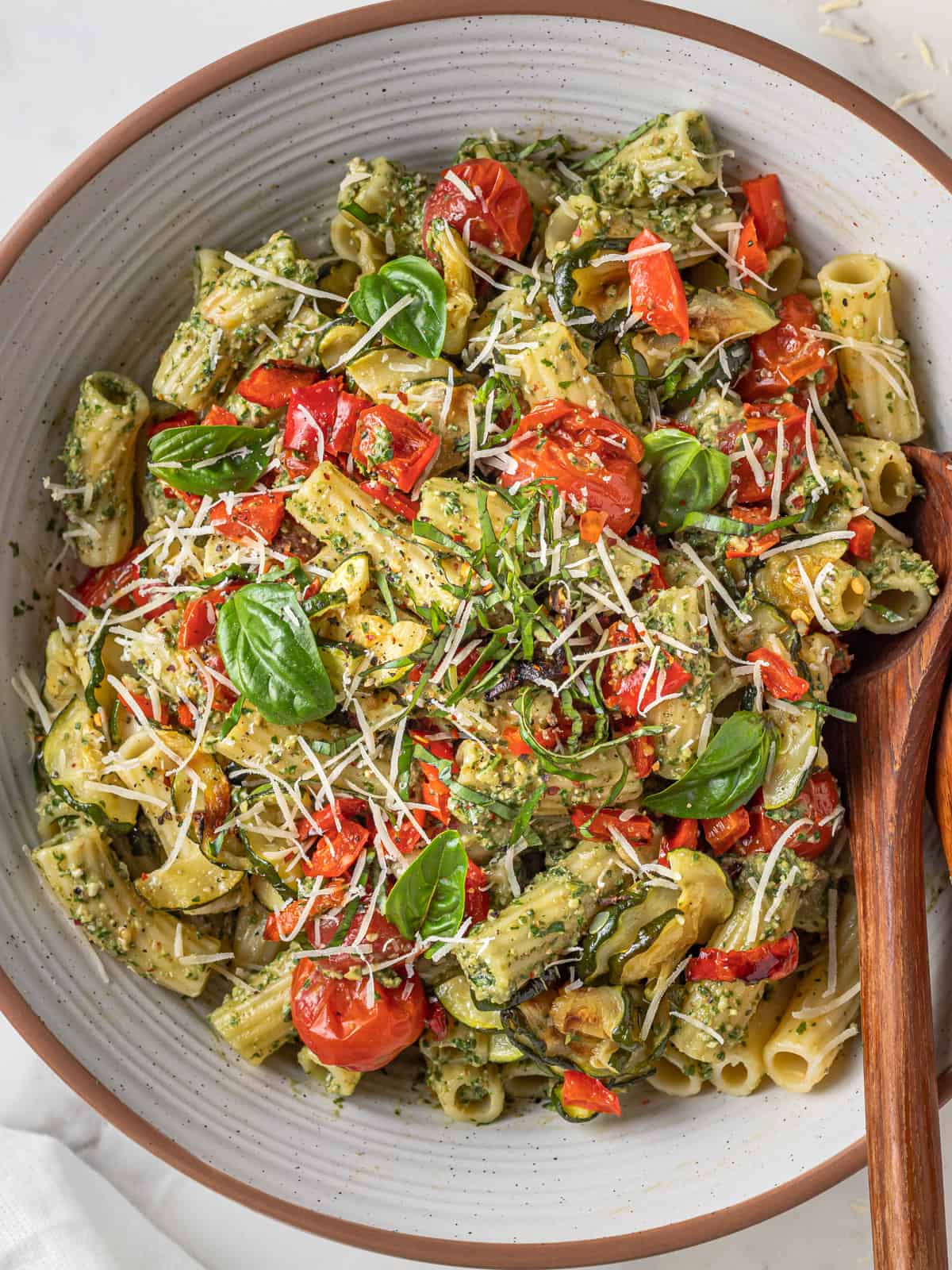 Bowl of veggies tossed with pesto and pasta.