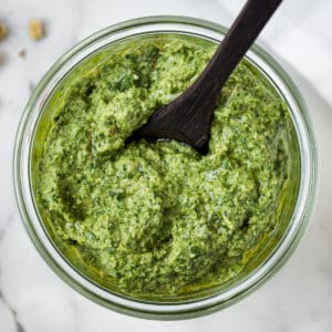 Dairy-free pesto in a bowl with a spoon dipped in.