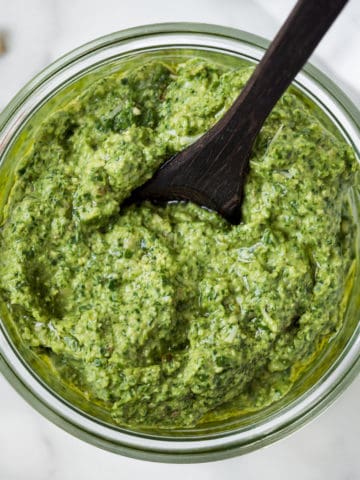 Dairy-free pesto in a bowl with a spoon dipped in.