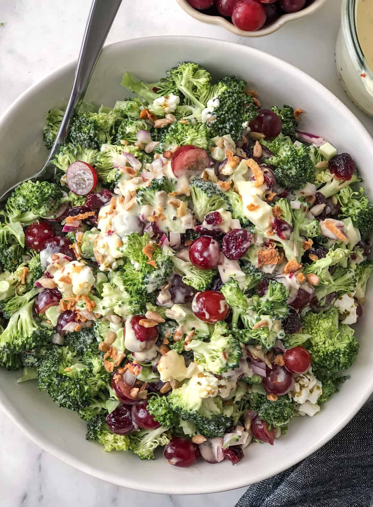 Bowlful of broccoli salad with grapes sunflower seeds and cranberries.