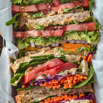 Sliced vegetable sandwiches stacked together in a tin.