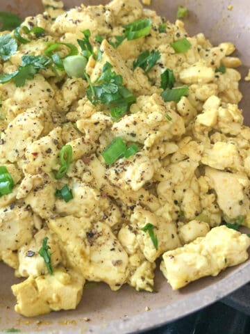 Skillet of fluffy tofu scrambled eggs with sliced green onions.