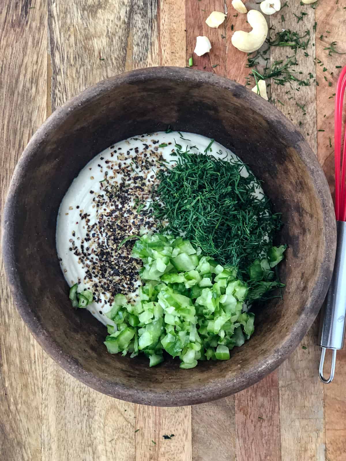 Tzatziki ingredients cashew cream, cucumbers and dill in a bowl.