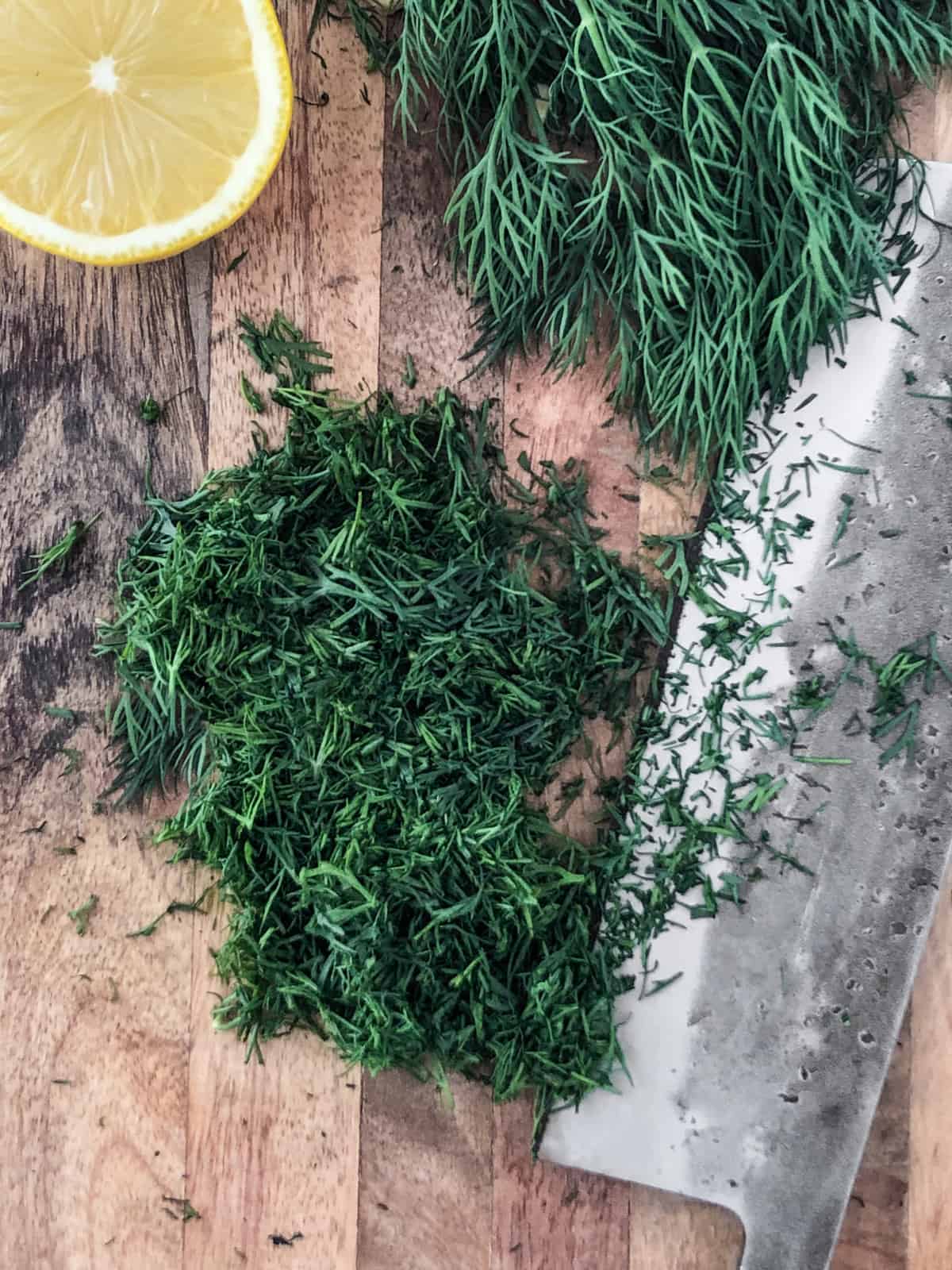Chopped dill on a cutting board with a knife.