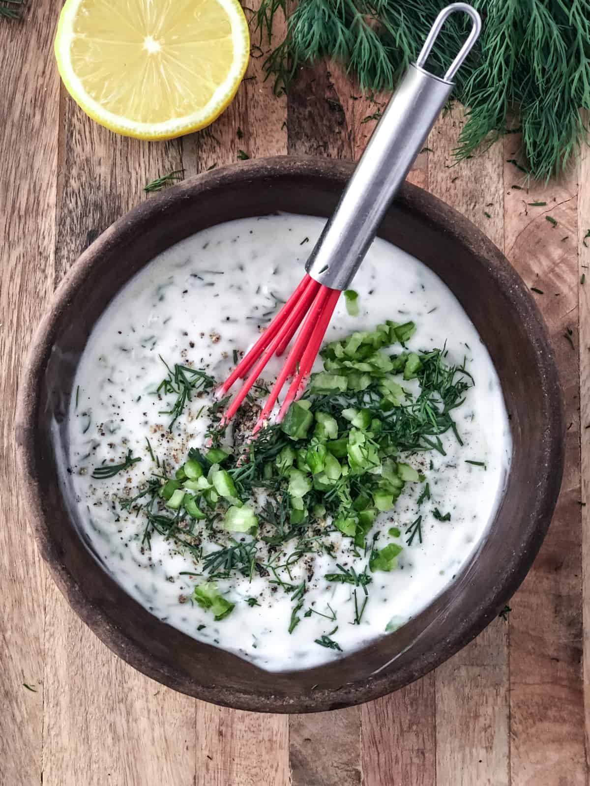 Dairy-free tzatziki sauce in a bowl with a whisk.