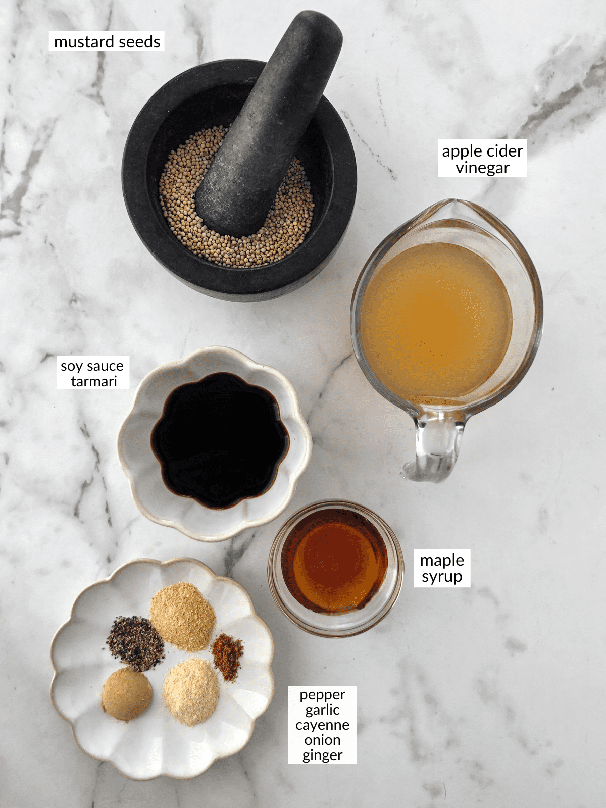 Ingredients for vegan worcestershire sauce in bowls on white counter.