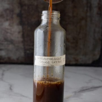 Worcestershire sauce substitute being poured from a measuring cup into a bottle.