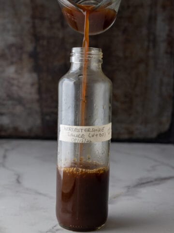 Worcestershire sauce substitute being poured from a measuring cup into a bottle.