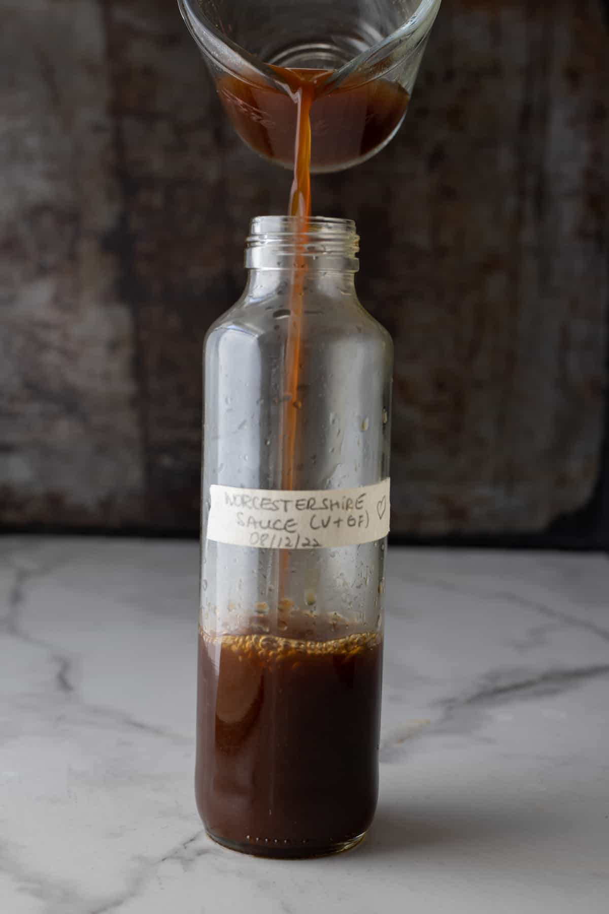 Worcestershire sauce substitute being poured from a measuring cup into a bottle.