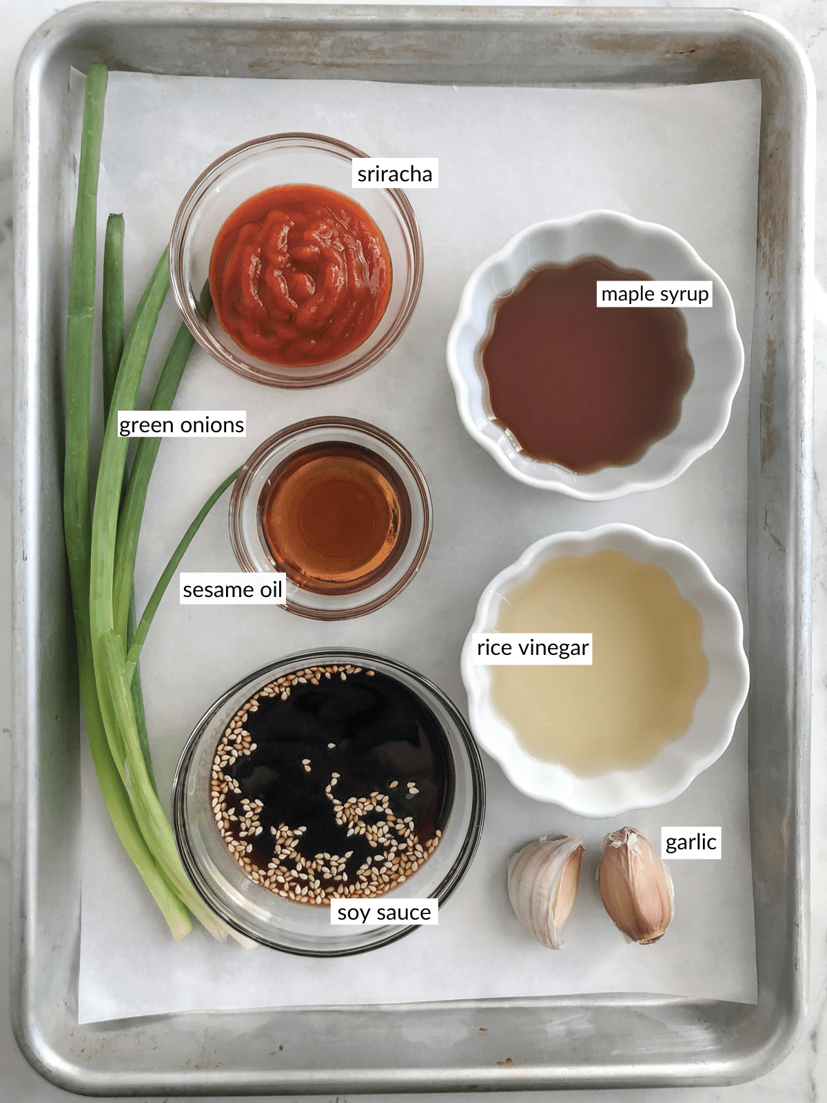Potsticker sauce ingredients in bowls on a baking sheet.
