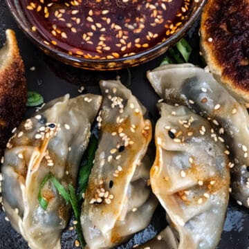 Bowl of dumpling sauce surrounded by gyoza dumplings.