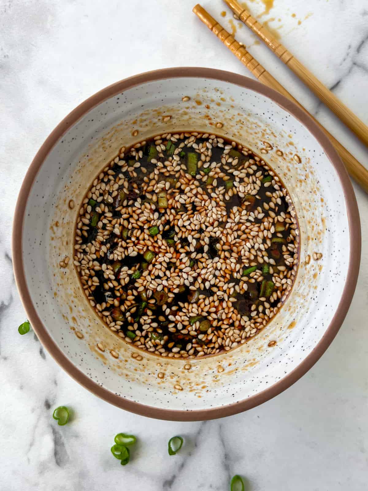 Bowlful of potsticker dipping sauce topped with sesame seeds.