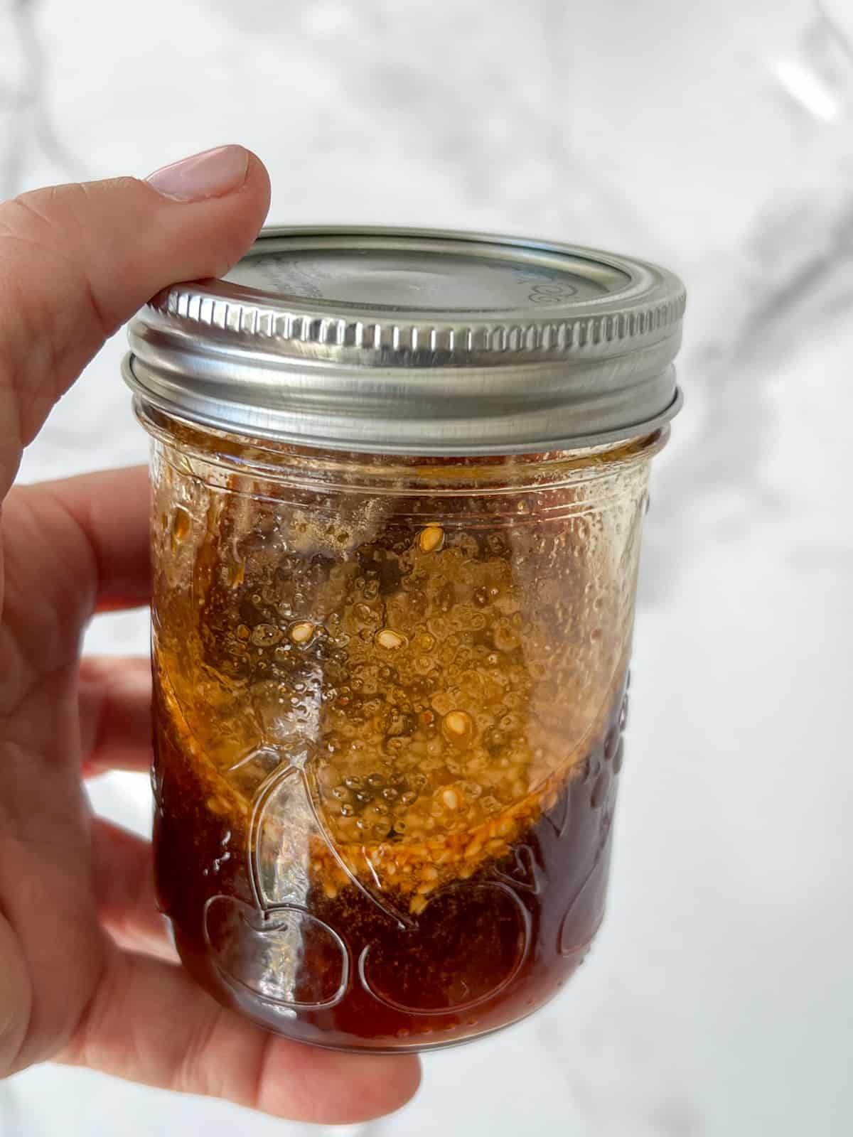 Hand shaking a jar of pot sticker dipping sauce.