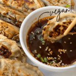 Veggie potstickers surrounding a bowl of dipping sauce.