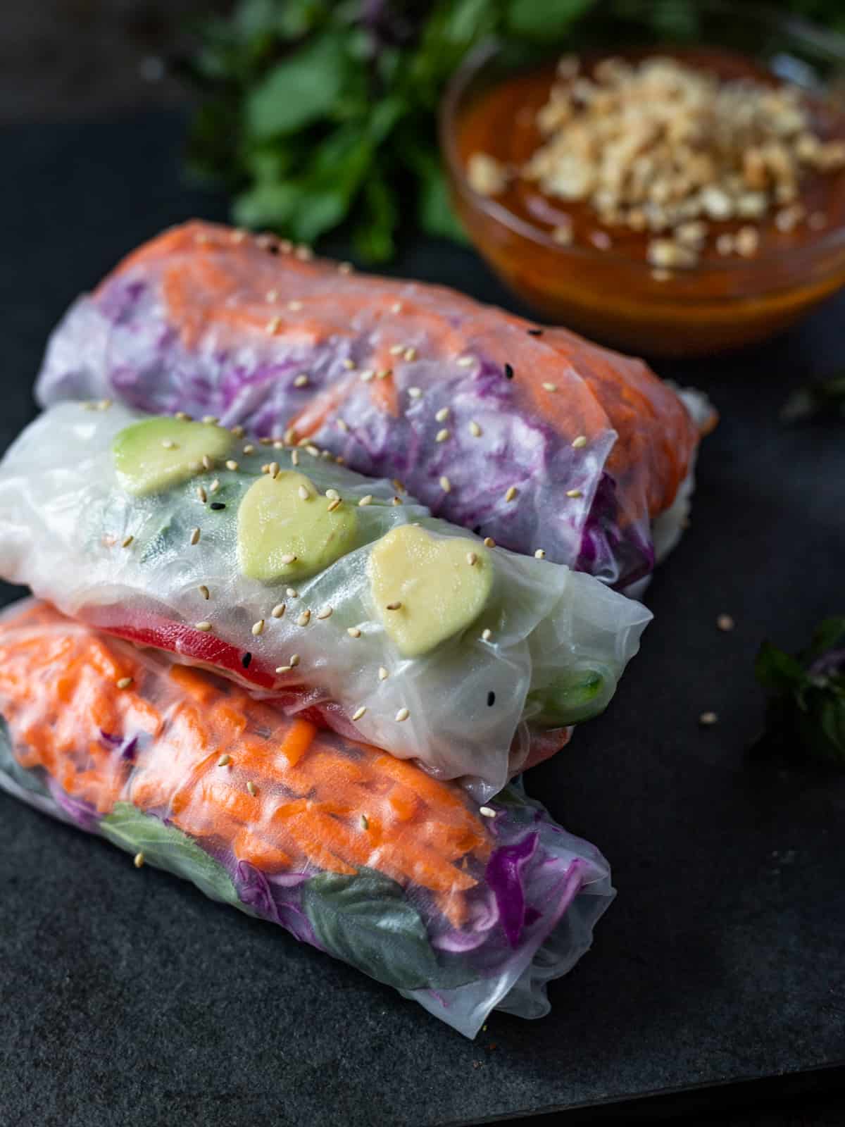 Three veggie salad rolls with a bowl of hoisin peanut sauce.