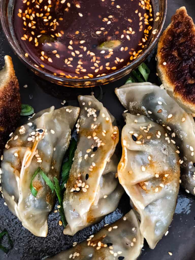 Potstickers and dipping sauce on a plate.