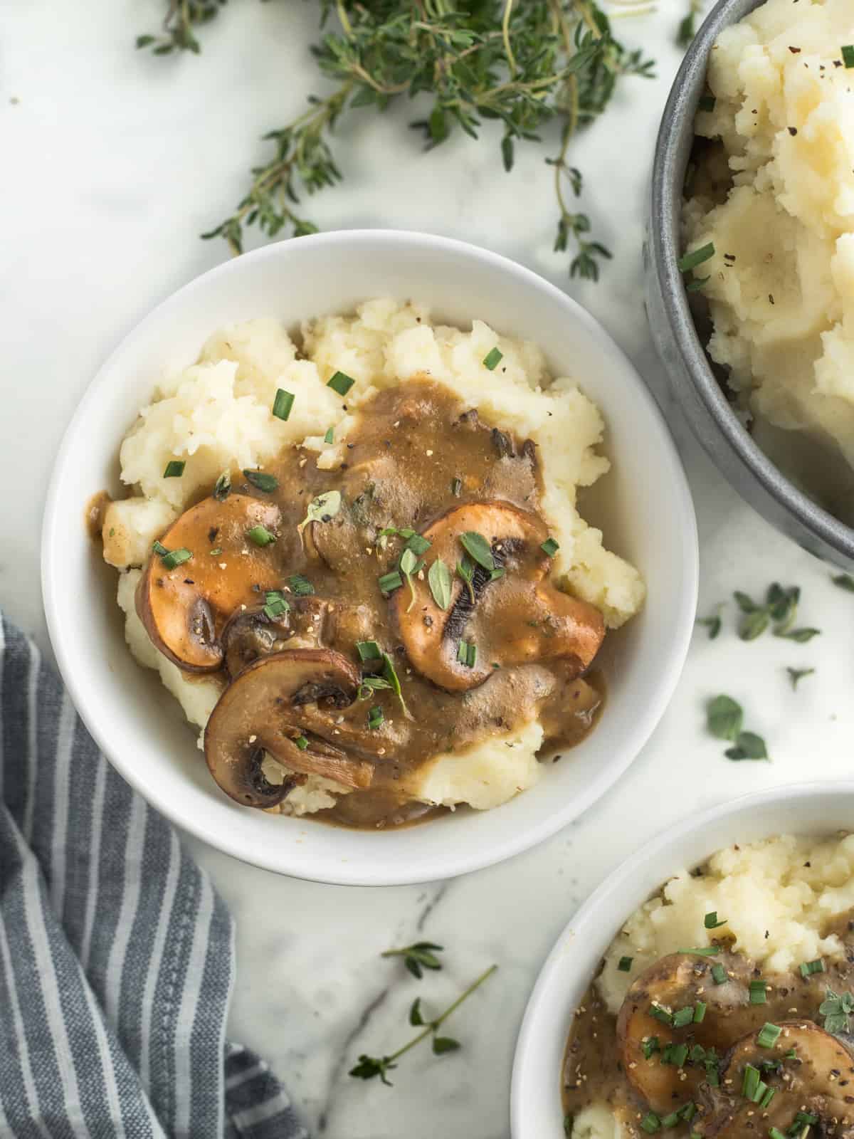 Bowl of mashed potatoes covered in mushroom gravy.