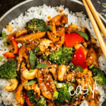 Bowl of stir fry veggies on rice with chopsticks.