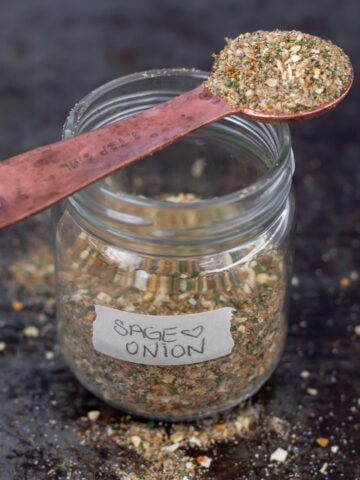 Jar of sage and onion seasoning with spoon on top.