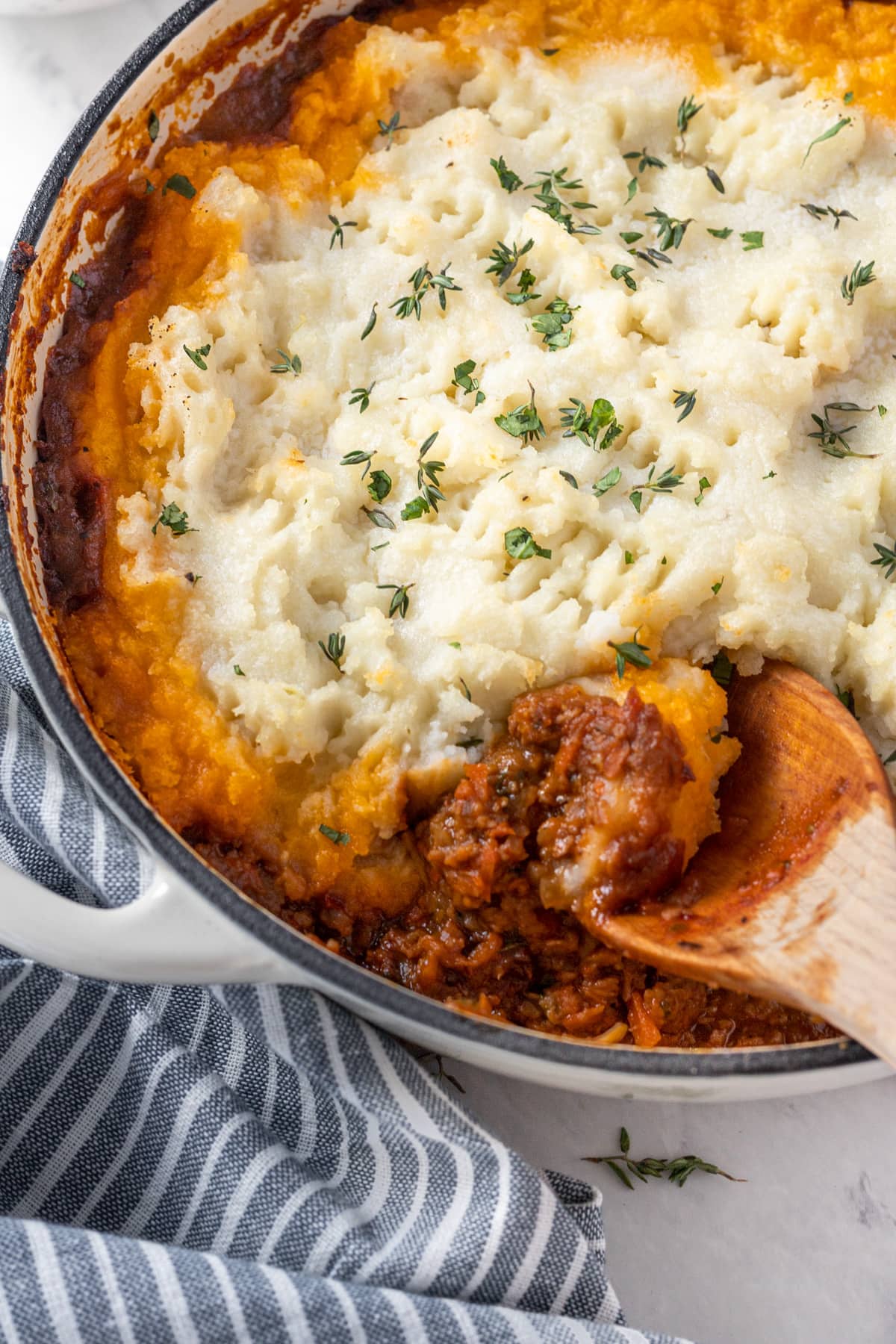 Casserole dish of veggie Shepherd's pie topped with mashed potatoes and fresh thyme. 