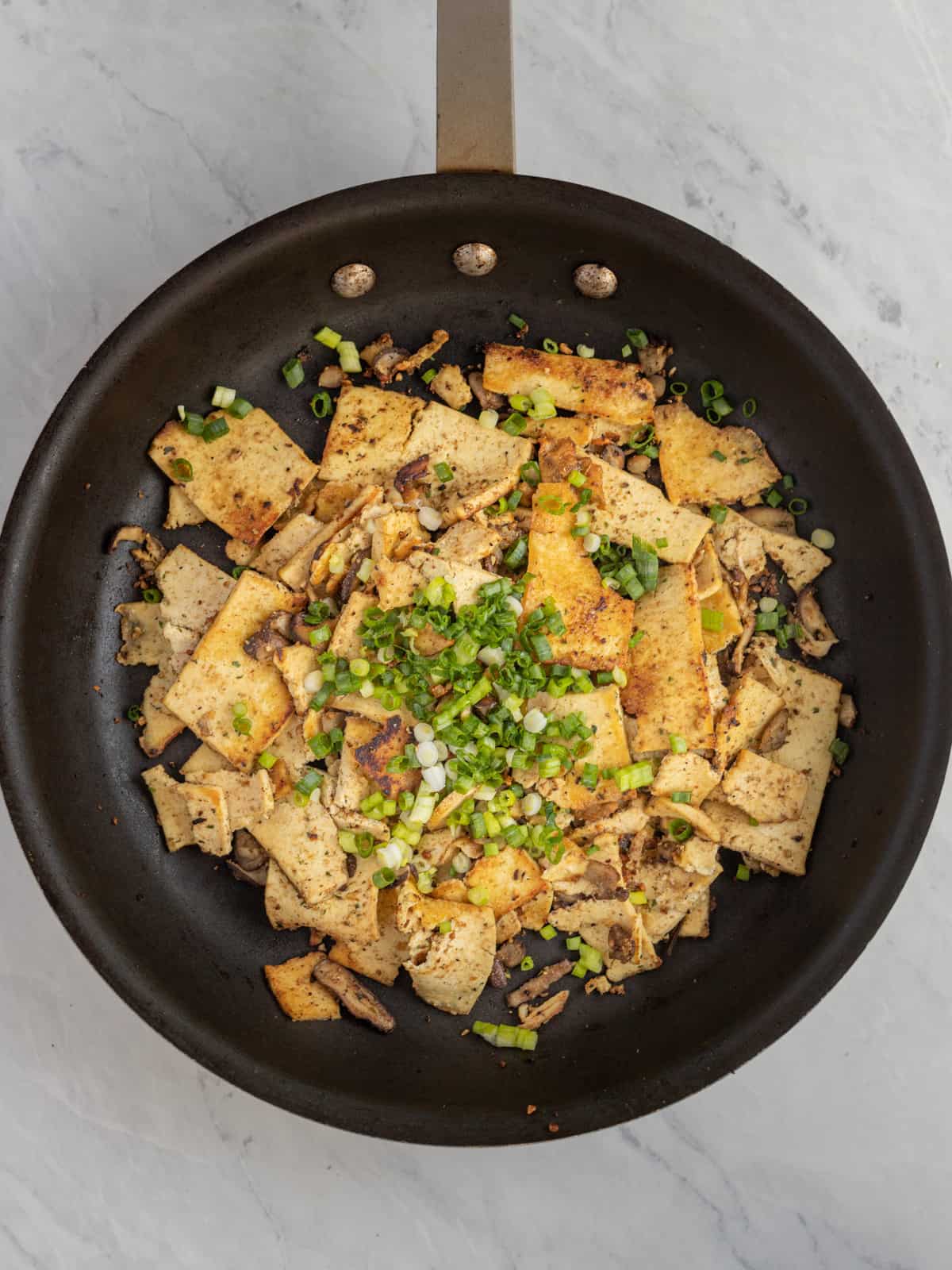 Large frying pan with cooked tofu and mushroom slices.