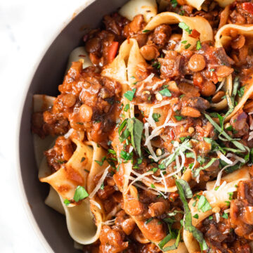 Bowl filled with lentil bolognese toss in pasta.