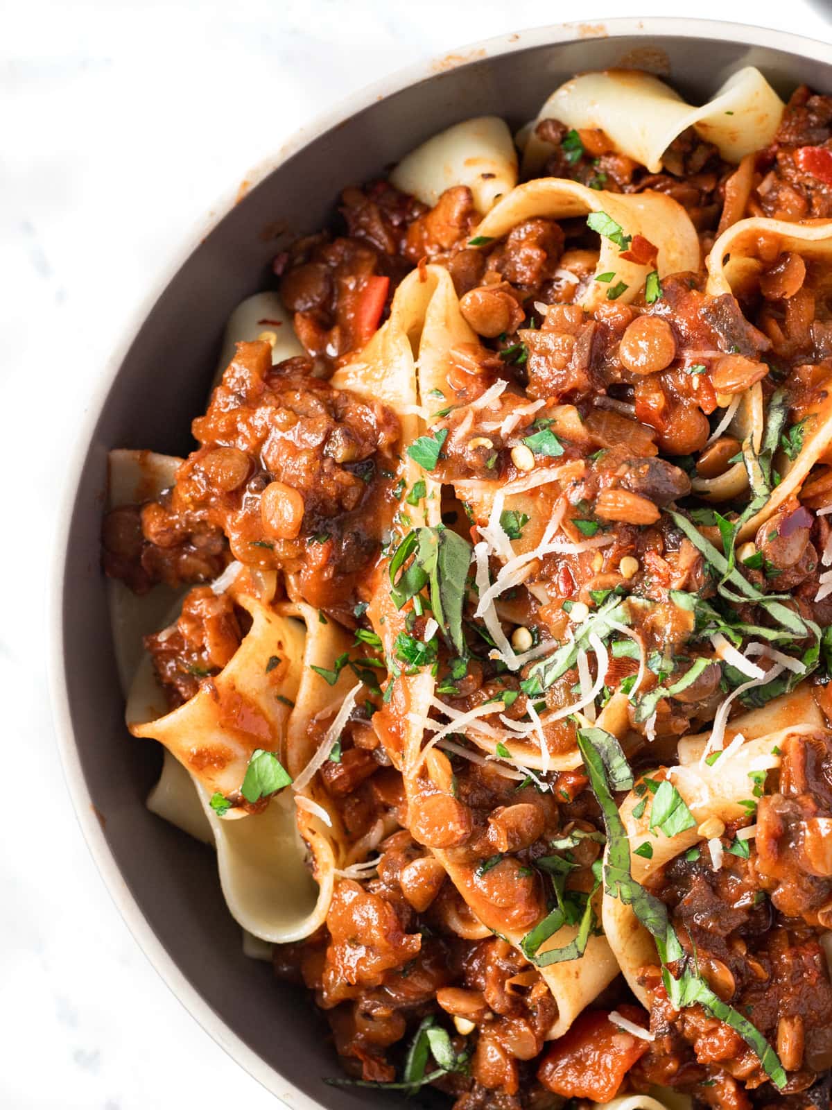 Bowl filled with lentil bolognese toss in pasta.