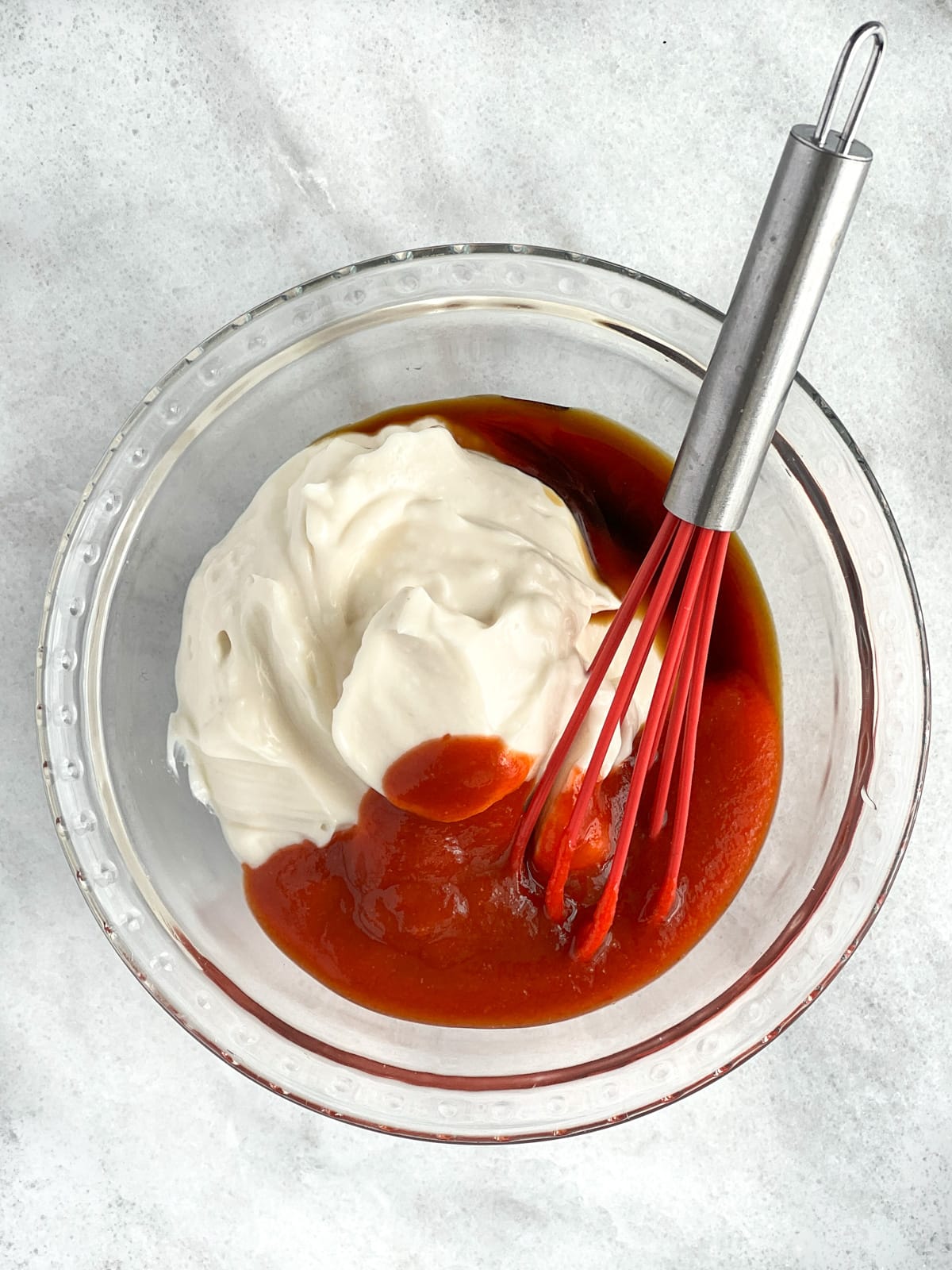 Ingredient for spicy mayo sauce in a bowl with a small red whisk.