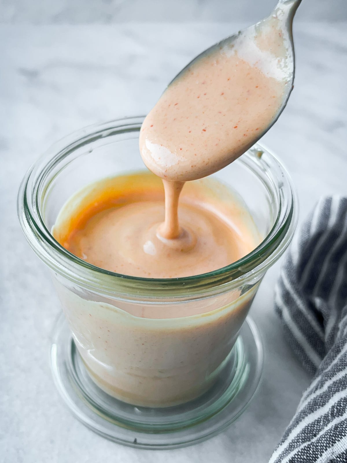 Spoonful of spicy sushi sauce being lifted from jar.