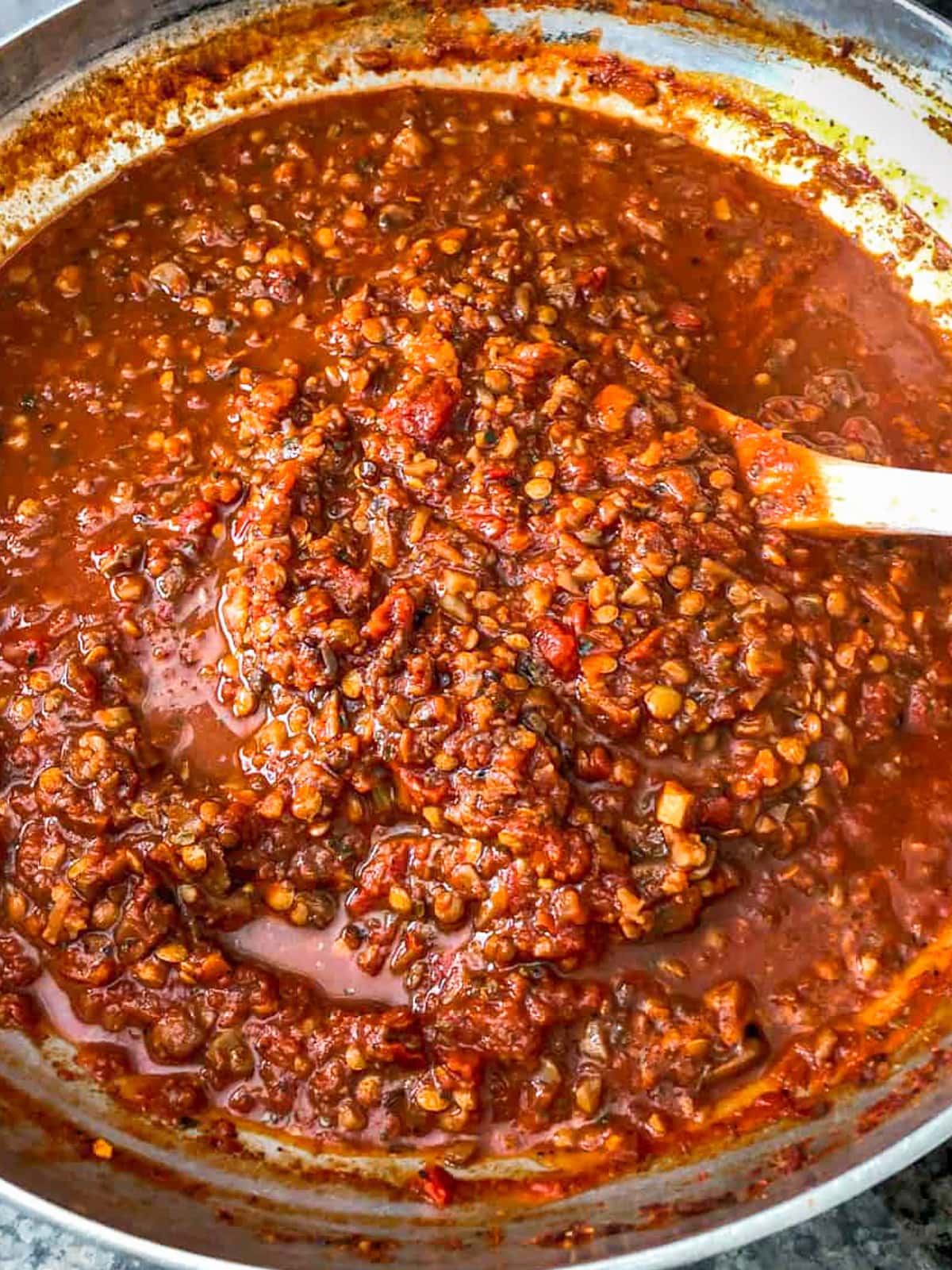 Pot of vegan bolognese being stirred on stove.