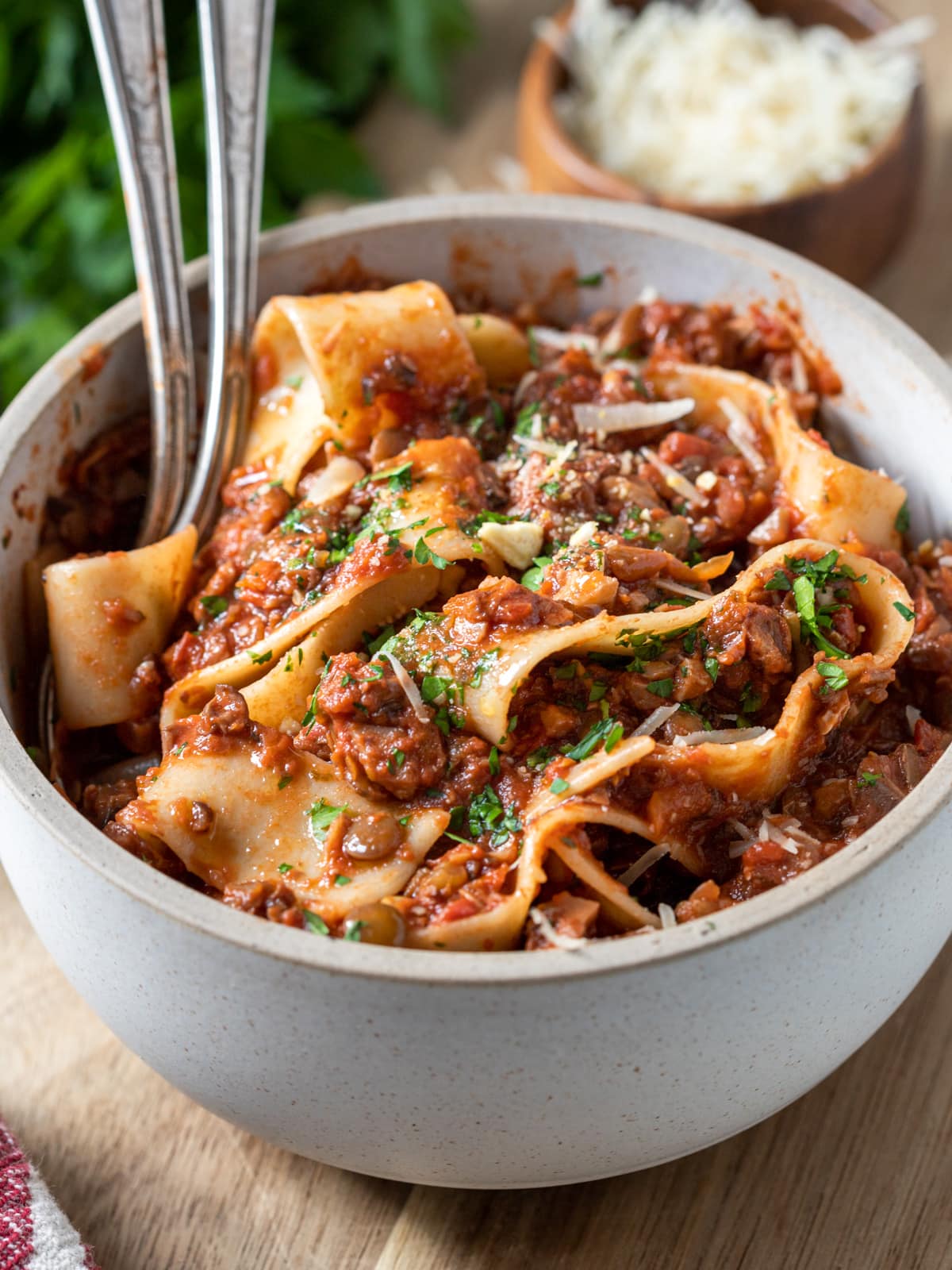 Bowl of pasta and vegetarian bolognese with a side dish of parmesan cheese.