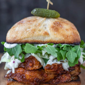 Spicy cauliflower burger with slaw and leafy greens topped with green pickle.