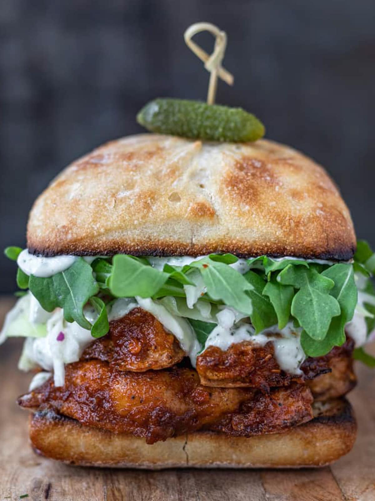 Spicy cauliflower burger with slaw and leafy greens topped with green pickle.