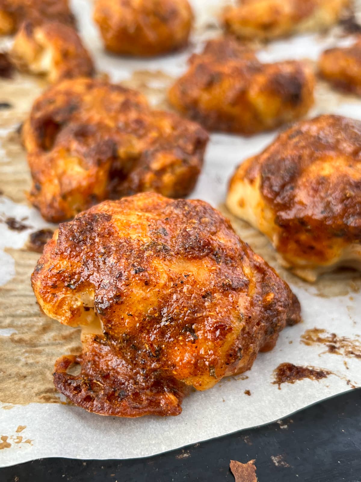 Baked cauliflower pieces slathered in a spicy sauce on a baking sheet.