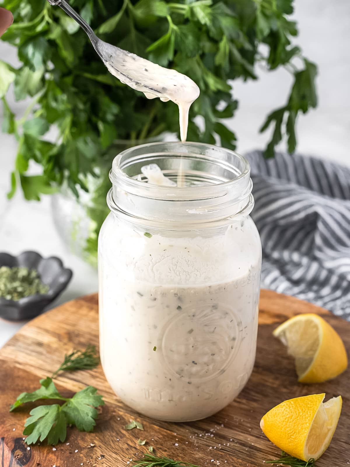 Spoonful of homemade ranch dressing being lifted out of a jar.